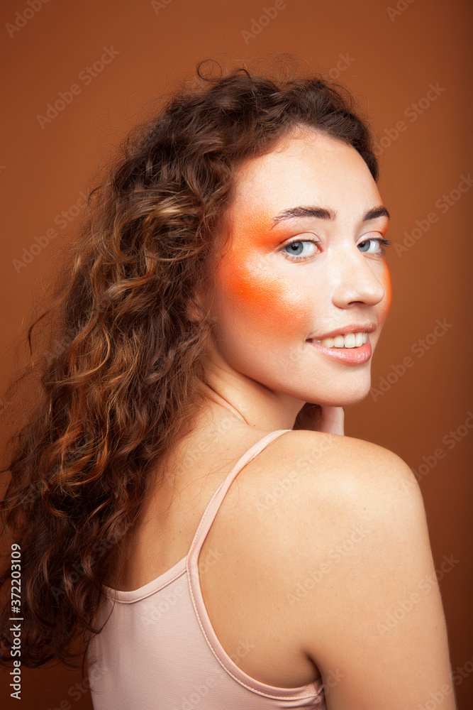 young pretty girl with curly hair posing cheerful on brown background, lifestyle people concept young pretty girl with curly hair posing cheerful on brown background, lifestyle people concept