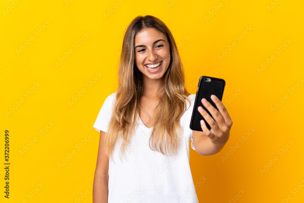 Young hispanic woman over isolated yellow background making a selfie with mobile phone Young hispanic woman over isolated yellow background making a selfie with mobile phone