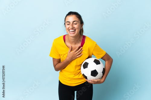 Young hispanic football player woman over isolated on blue background smiling a lot © luismolinero