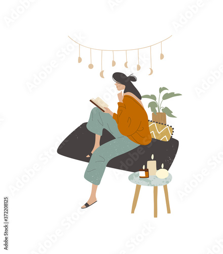 Girl woman lady reading at home house sitting on sofa couch wearing home clothes domestic clothing dress outfit wear, with candles on coffee table end table