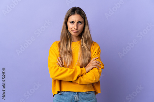 Young hispanic woman over isolated purple background with unhappy expression © luismolinero