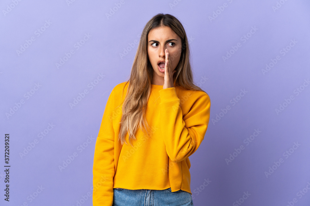 Young hispanic woman over isolated purple background whispering something with surprise gesture while looking to the side Young hispanic woman over isolated purple background whispering something with surprise gesture while looking to the side