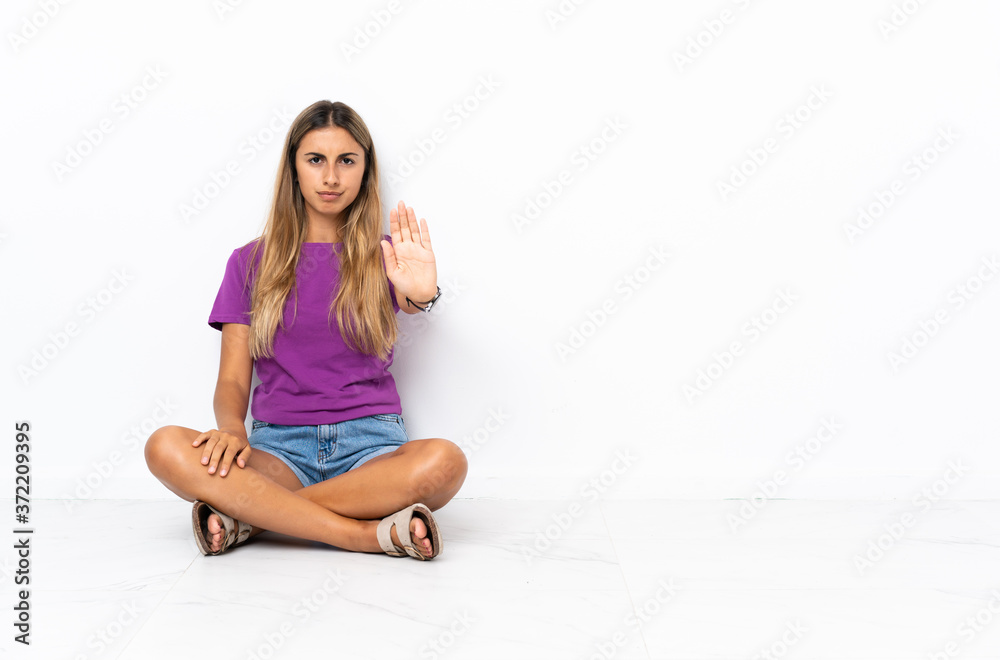 Young hispanic woman sitting on the floor making stop gesture Young hispanic woman sitting on the floor making stop gesture