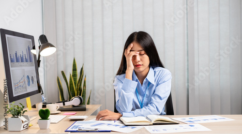 Working Asian women feel stressed, tired from work, migraine headaches from hard work while working at the office