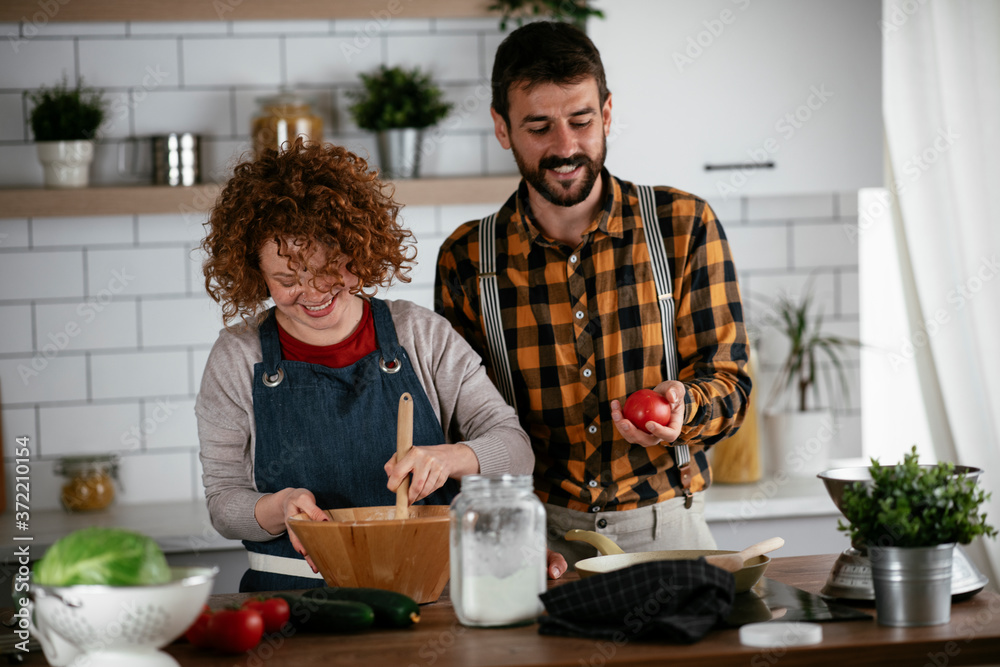 Young couple making delicious food at home. Loving couple enjoying in the kitchen.. Young couple making delicious food at home. Loving couple enjoying in the kitchen..