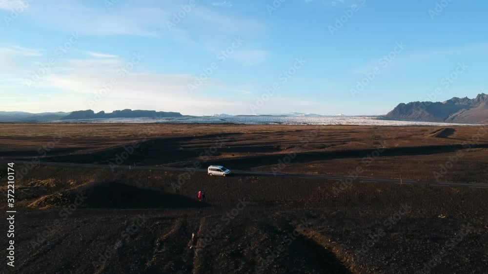 A wonderful drone shot of two travelers and a camper van with lake and mountains background. A wonderful drone shot of two travelers and a camper van with lake and mountains background.