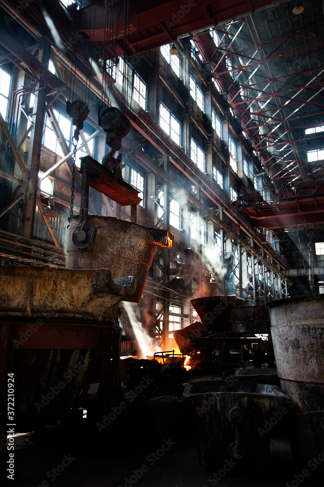 Metallurgy factory workshop. Orange hot melted metal and white smoke (steam). Taraz city, Kazakhstan.