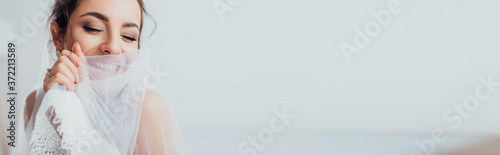 Horizontal crop of young bride with closed eyes holding veil photo