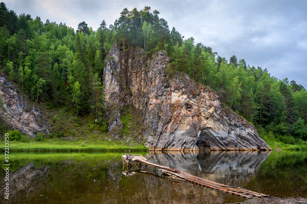 An epic landscape of Ural nature on the Chusovaya river with large rocks along the river.