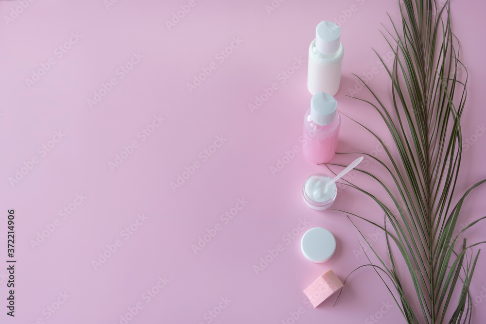 Bottles and container for cosmetic products with green herbal leaves, packaging with blank labels for branding. Pink background, copy space, natural organic cosmetic products concept Bottles and container for cosmetic products with green herbal leaves, packaging with blank labels for branding. Pink background, copy space, natural organic cosmetic products concept