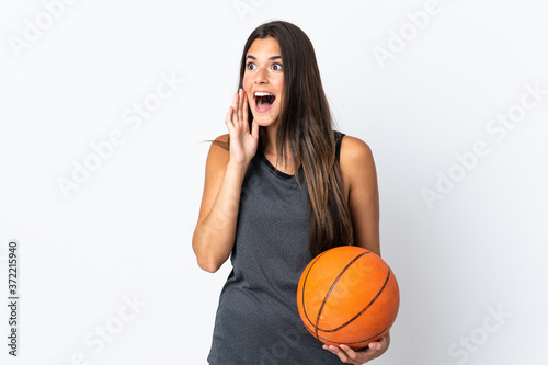Young brazilian woman playing basketball isolated on white background shouting with mouth wide open to the side © luismolinero