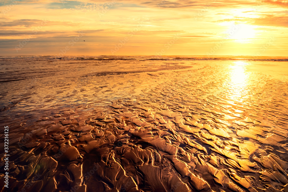 Golden embossed textured sand on the ocean at low tide and golden dawn. Golden sunrise on the ocean.