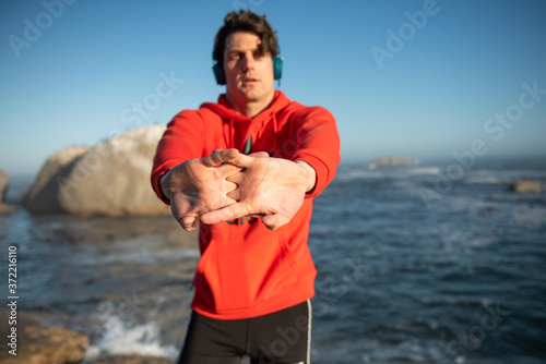 young man warming up before running on the beach