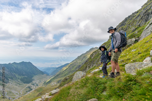 Father and son on top of the mountain, hiking with bakpacks in sunny day. Mountain scenery