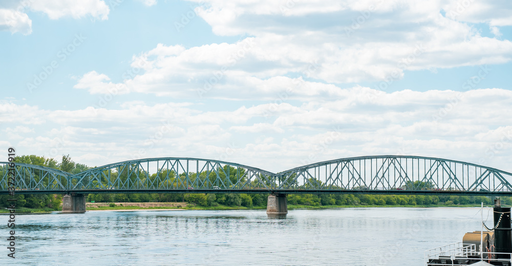 Fototapeta premium Photography road bridge over Vistula River in Torun (Pilsudski Bridge), Poland. Heavy rusty steel old industrial vehicle overpass. Landscape city view from boulevard.