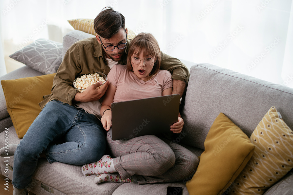 Young couple watching movie on lap top. Loving couple enjoying at home..