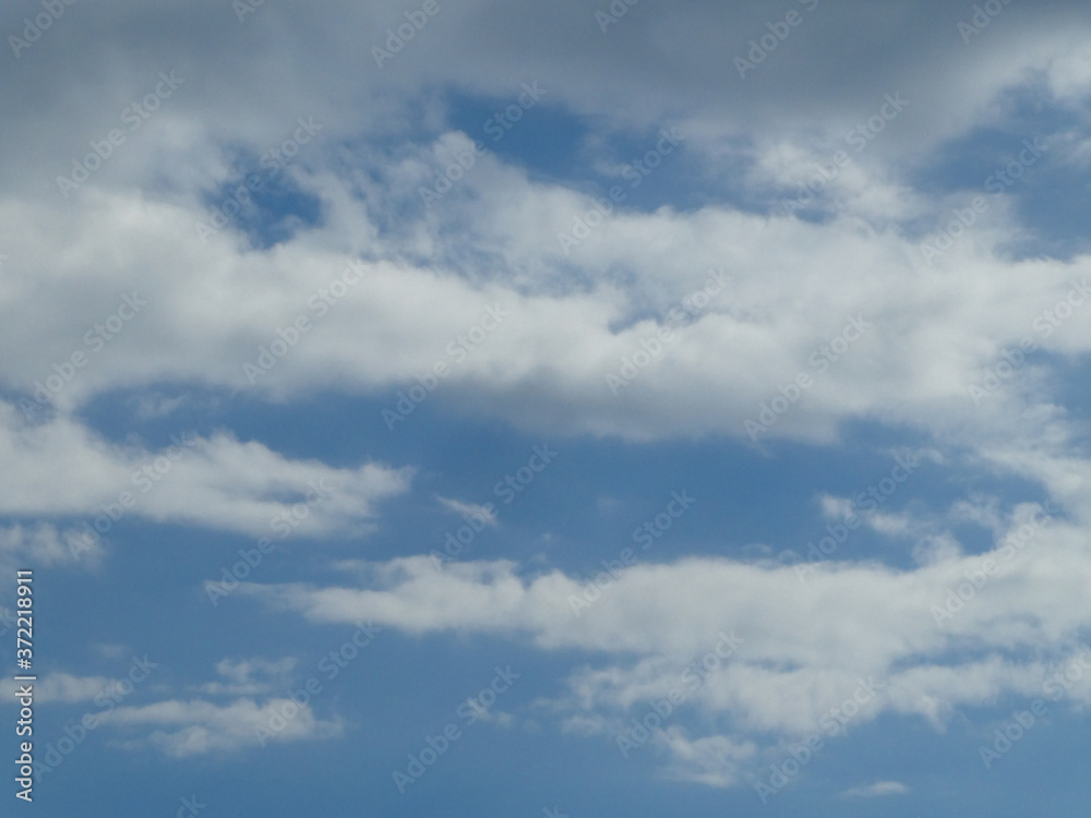 The blue cloudy sky with white clouds background and texture