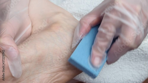 A woman peels her feet. Cleaning the skin of the feet with a cosmetic brush. Spa treatments at home.