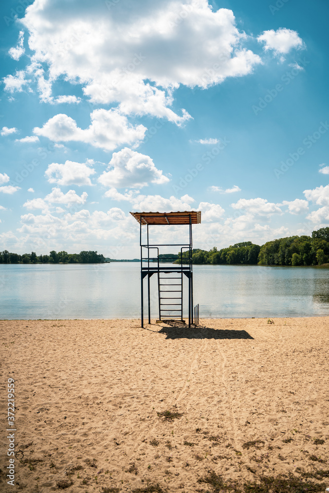Blue lifeguard rescue tower on a sandy beach in Kruszwica. Romantic travel, summer season, vacation beach relax concept. Idyllic quiet place for rest in the sun. 