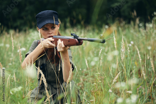 Woman on nature A shelter with a weapon looks into the scope green leaves 