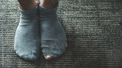 A pair of feet wearing old, dirty, and torn socks