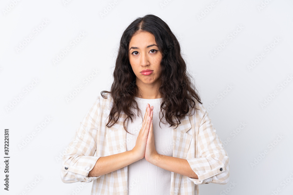 Mixed race woman over isolated white background keeps palm together. Person asks for something Mixed race woman over isolated white background keeps palm together. Person asks for something