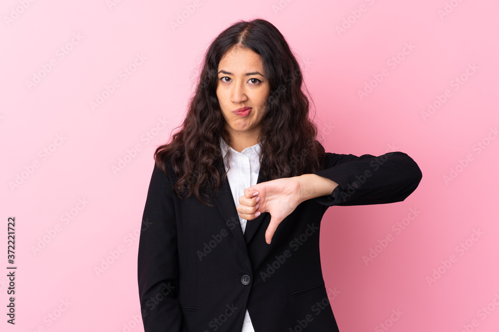 Mixed race business woman over isolated pink background showing thumb down sign Mixed race business woman over isolated pink background showing thumb down sign