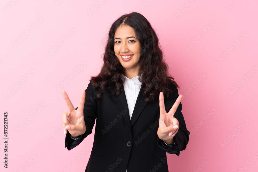 Mixed race business woman over isolated pink background smiling and showing victory sign Mixed race business woman over isolated pink background smiling and showing victory sign