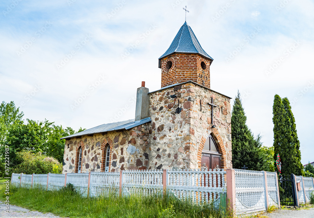 Small vintage christian catholic chapel. Brick building with gothic wooden gate with fittings.Worship village building. Old religion prayer church.
