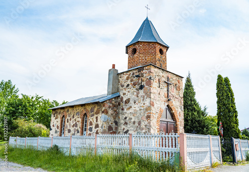 Small vintage christian catholic chapel. Brick building with gothic wooden gate with fittings.Worship village building. Old religion prayer church.