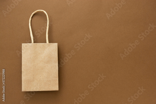 Craft brown paper shopping bag isolated on brown background, copy space.