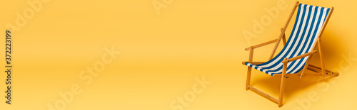 Photo horizontal image of striped blue and white deckchair on yellow background