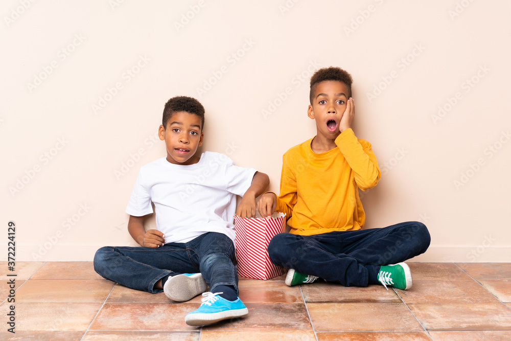 African American brothers  holding popcorns and doing surprise gesture