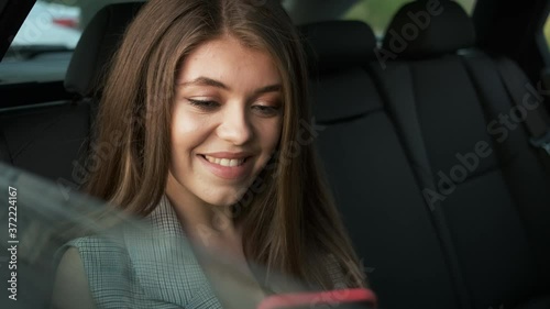 Successful Caucasian woman in a stylish suit sits in the car and solves work issues over the phone