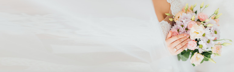 Panoramic shot of bride in wedding dress touching flowers in bouquet