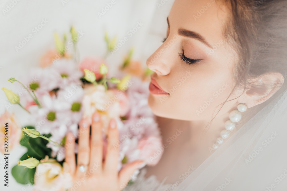 Selective focus of bride with closed eyes touching bouquet Selective focus of bride with closed eyes touching bouquet