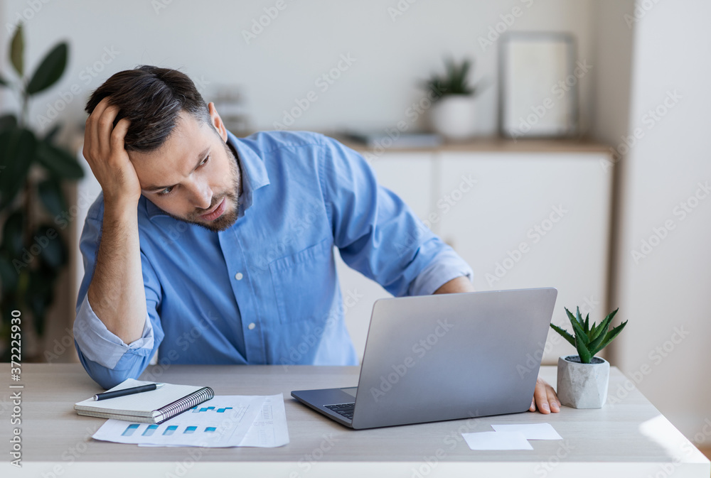 Stressed tired businessman having problems at work, sitting at desk with laptop Stressed tired businessman having problems at work, sitting at desk with laptop
