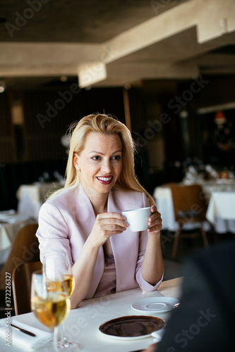 Beautiful businesswoman dressed in the suit drinking coffee. Businessman and businesswoman enjoying in the restaurant.