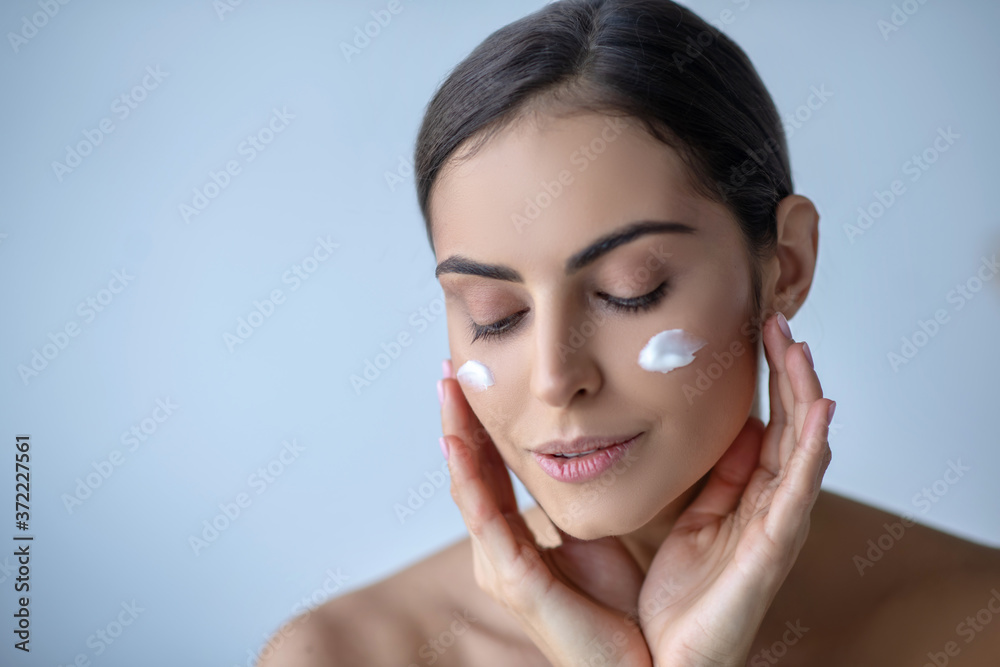 Cute woman with cream on her cheeks looking relaxed