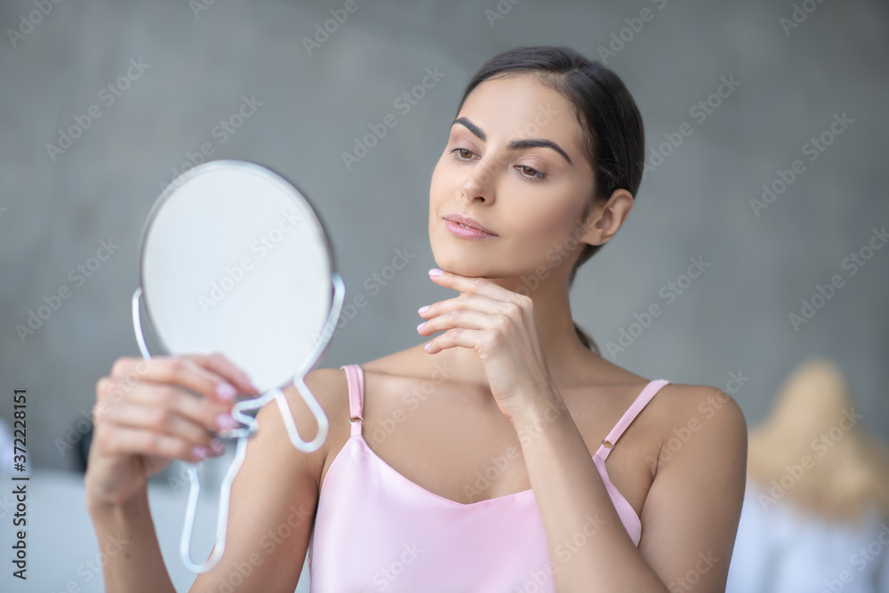 Cute woman in pink lingerie looking in the mirror Cute woman in pink lingerie looking in the mirror