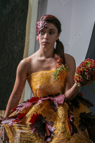 Concept portrait for an Italian woman with olive skin and with gathered hair and autumn leaves on her head and elegant low-cut dress to represent autumn