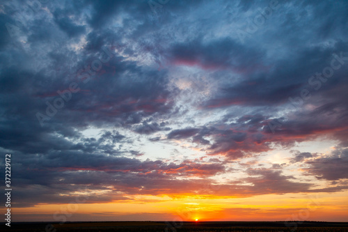 Grey fluffy clouds on sky over hill during sunrise
