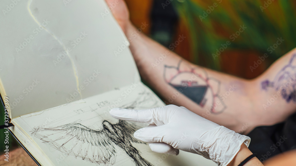Female Tattoo Artist Showing Tattoo Design to the Client