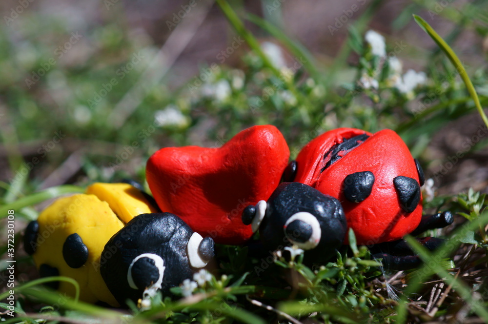 Figures of two ladybirds in the green grass. Next to the heart. Figures of two ladybirds in the green grass. Next to the heart.