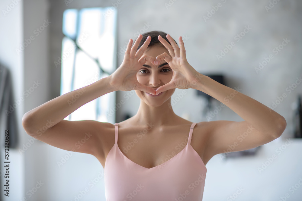 Woman in pink showing heart sign and feeling happy