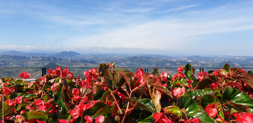 Panorama of the San Marino landscape with red begonias. Stunning view of the San Marino mountains on a sunny, summer day.