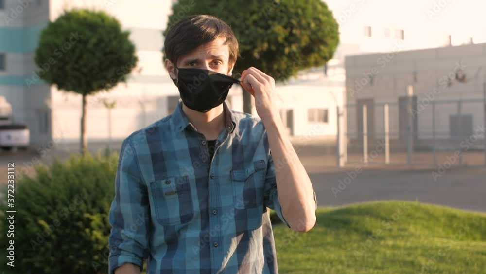 Young handsome man in the shirt is glad that quarantine has ended, takes off his medical mask and throws it away Young handsome man in the shirt is glad that quarantine has ended, takes off his medical mask and throws it away
