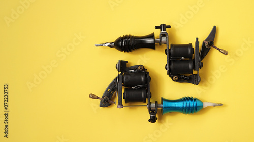 Two tattoo machines on a yellow background - tattoo industry photo