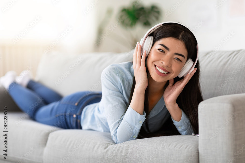 Weekend Pastime. Positive Asian Girl Wearing Wireless Headphones, Listening Music At Home Weekend Pastime. Positive Asian Girl Wearing Wireless Headphones, Listening Music At Home