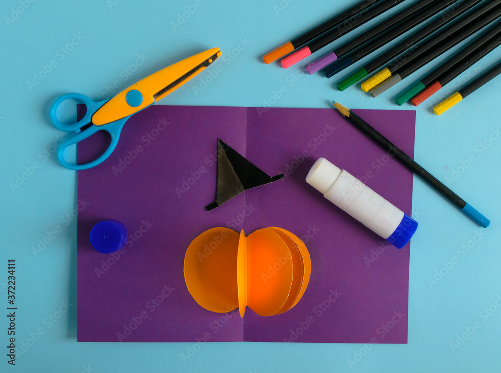 Diy Halloween card with pumpkin on purple background.Gift idea, decor Halloween.Instruction.Step by step.Top view. Children Halloween craft. Workshop.Flat lay. Step 8 Diy Halloween card with pumpkin on purple background.Gift idea, decor Halloween.Instruction.Step by step.Top view. Children Halloween craft. Workshop.Flat lay. Step 8